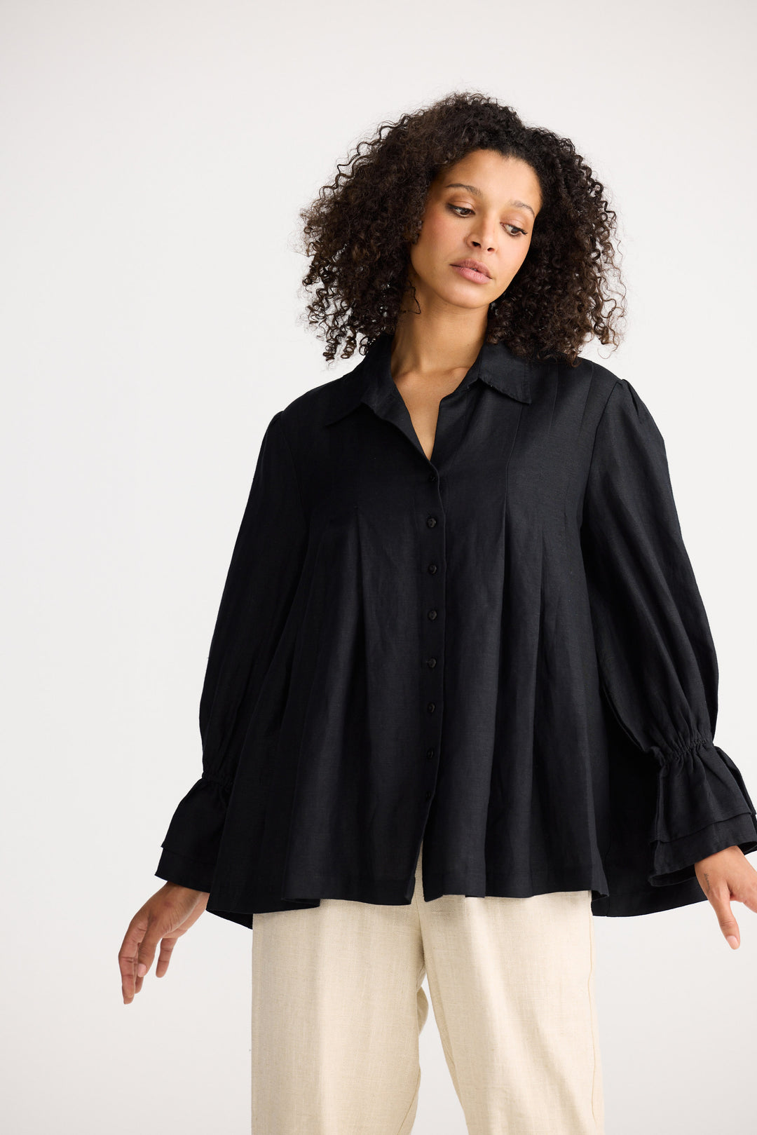 Woman wearing a black blouse with long sleeves on a white background