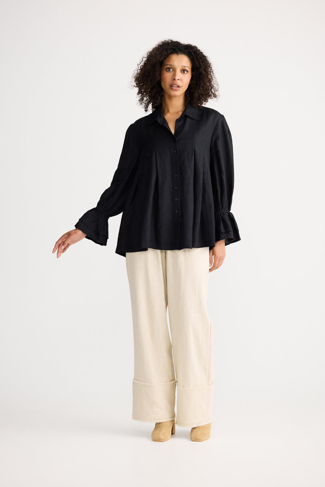 Woman wearing a black blouse and beige pants on a white background