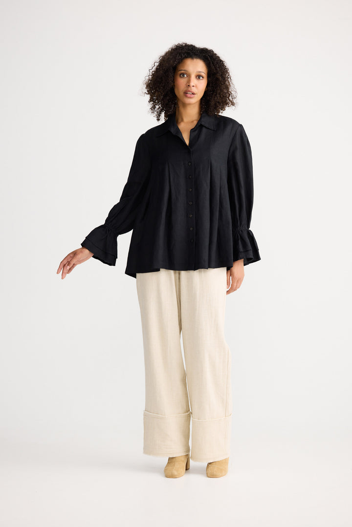 Woman wearing a black blouse and beige pants on a white background