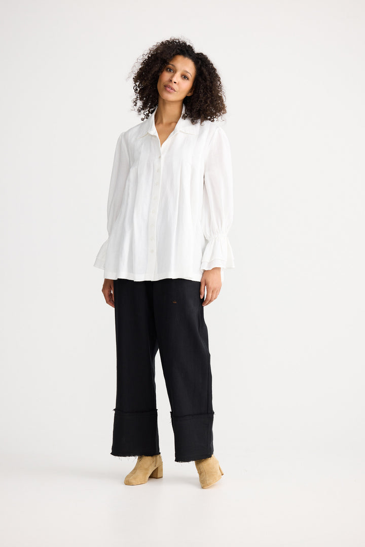 Woman wearing a white blouse and black pants on a white background