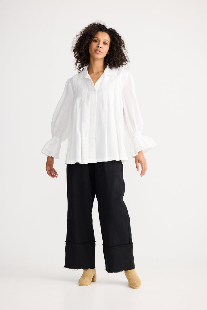 Woman wearing a white blouse and black pants on a white background