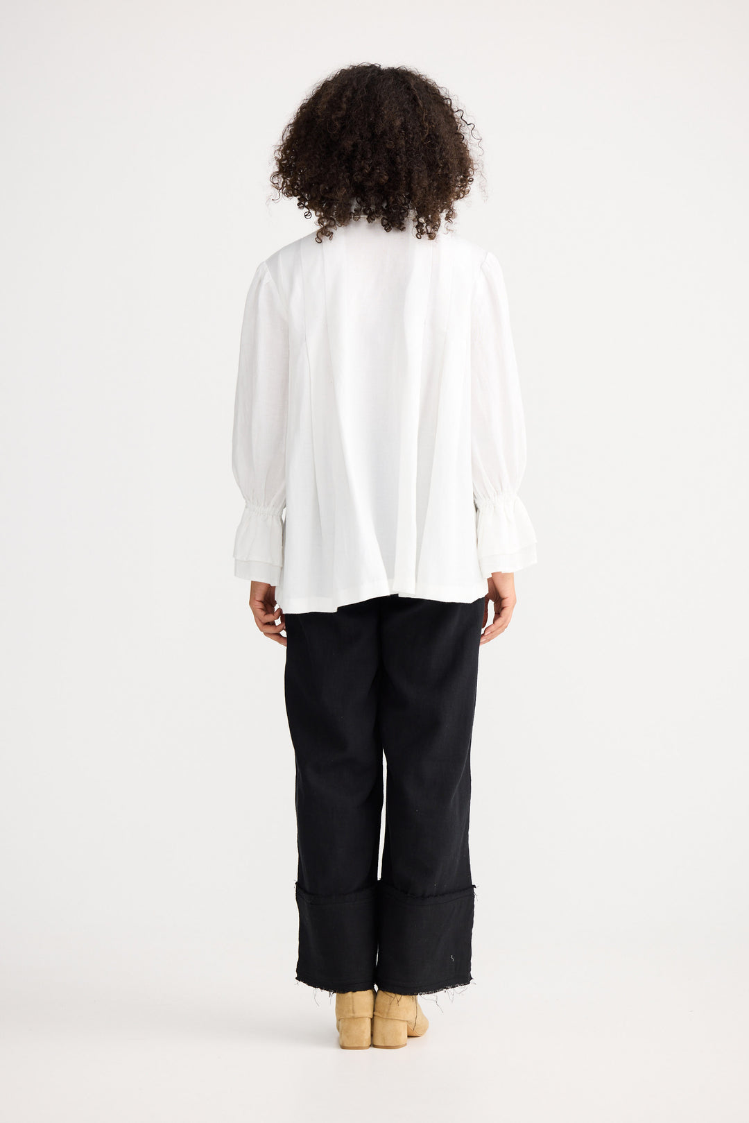 Person wearing a white blouse and black pants on a white background