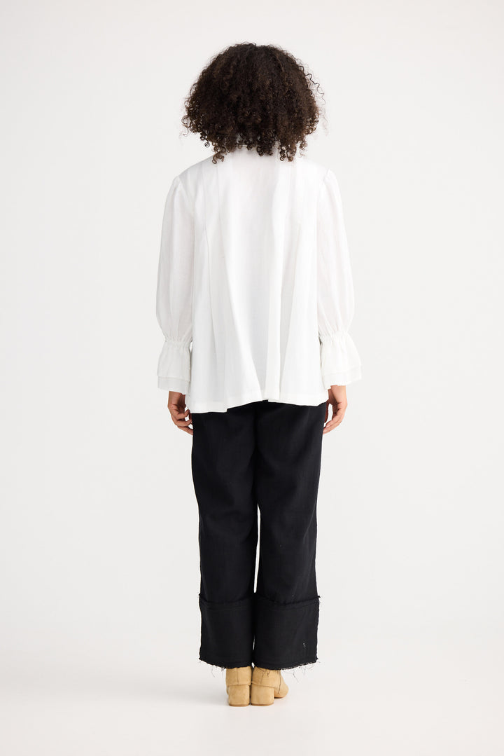 Person wearing a white blouse and black pants on a white background