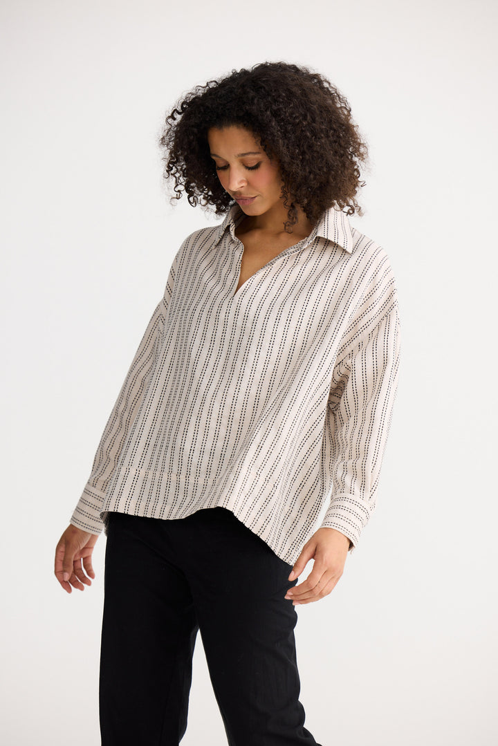 Model wearing natural stitch Wander Long Sleeve Top, side view on white background