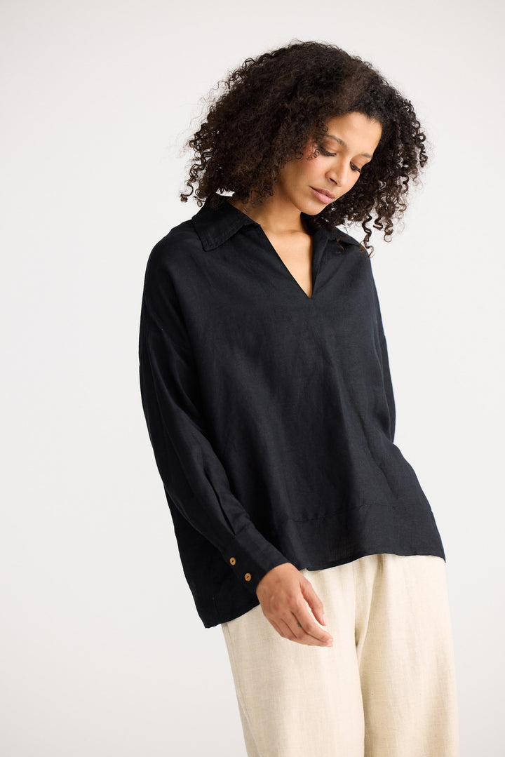 Woman wearing a black blouse with a plain background