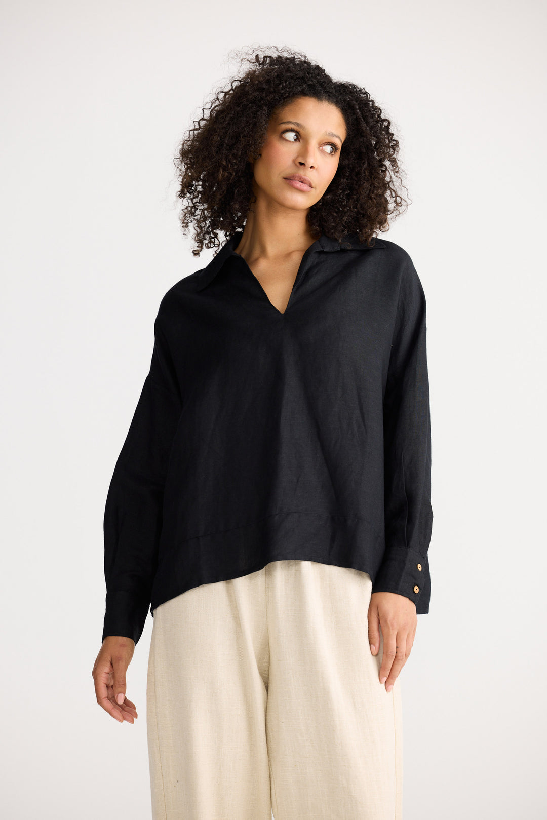 Woman wearing a black blouse and beige pants on a white background