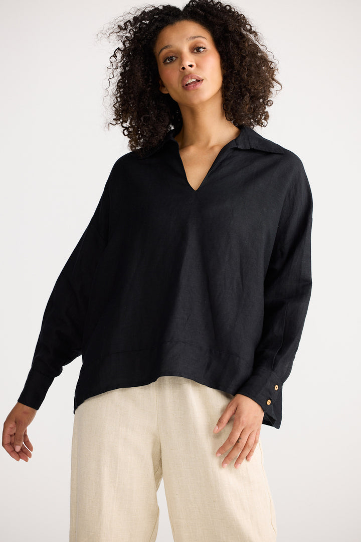 Woman wearing a black shirt and beige pants on a white background