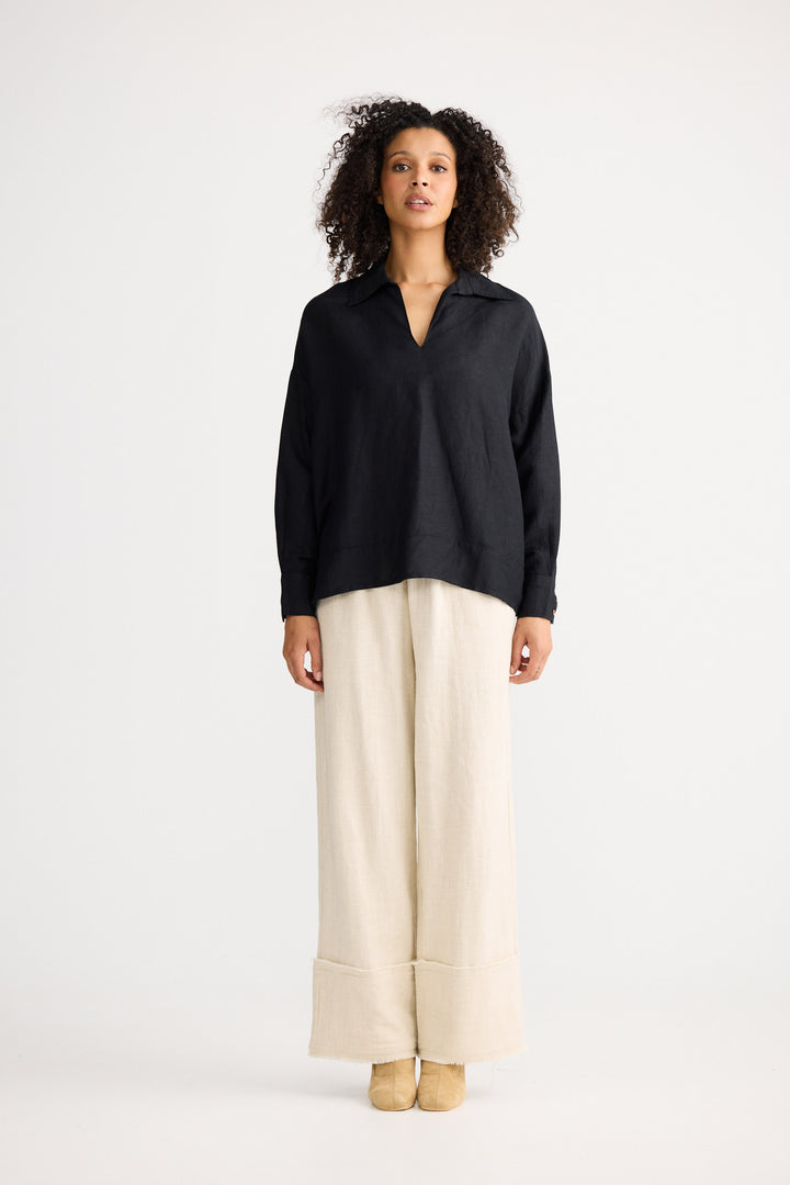 Woman wearing a black blouse and beige pants on a white background