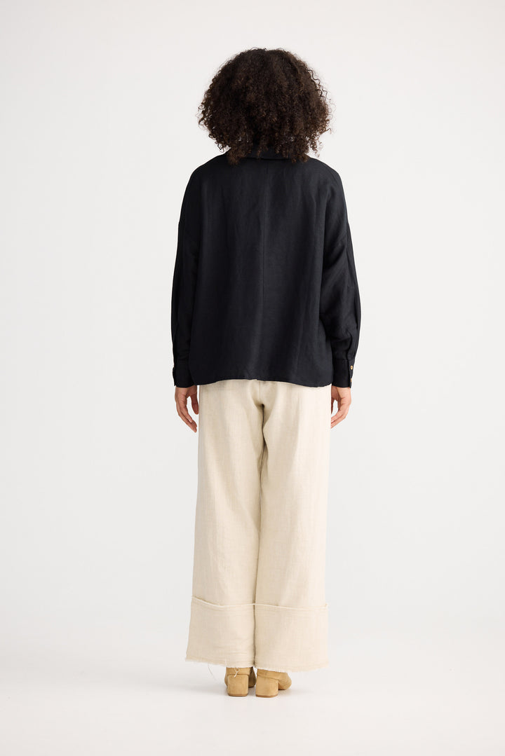 Person wearing a black top and beige pants on a white background
