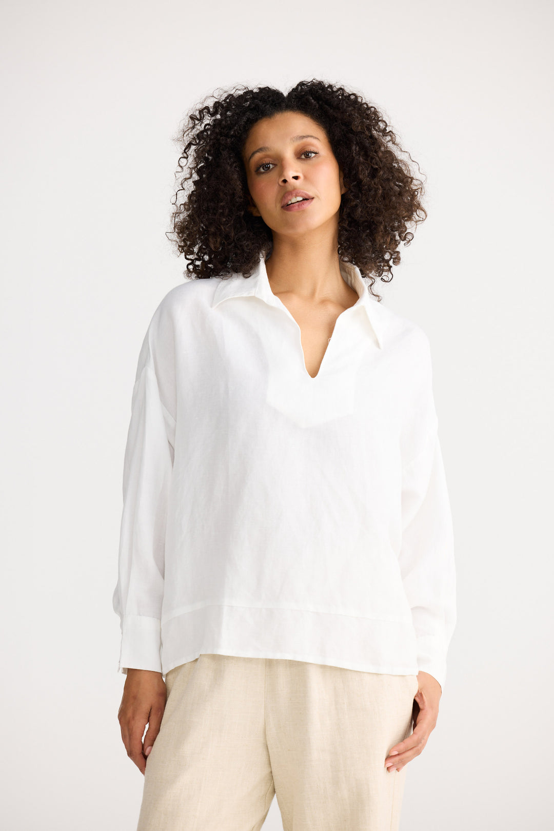 Woman wearing a white shirt and beige pants against a white background