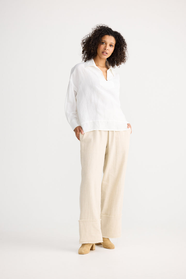 Woman wearing a white blouse and beige pants on a white background