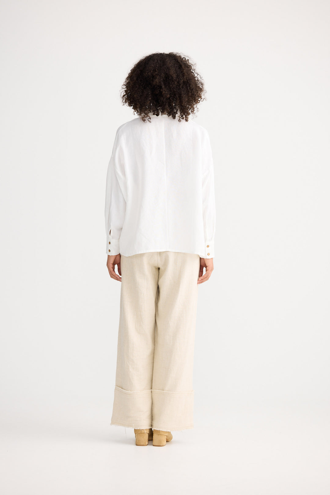 Person wearing a white shirt and beige pants on a white background