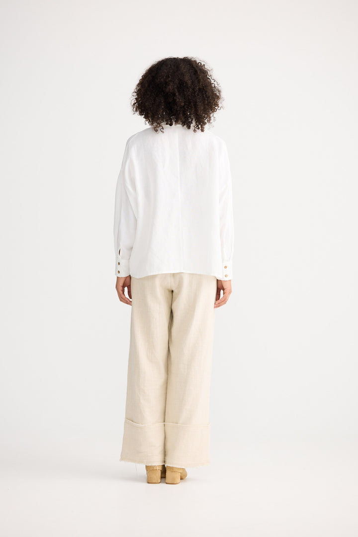 Person wearing a white shirt and beige pants on a white background