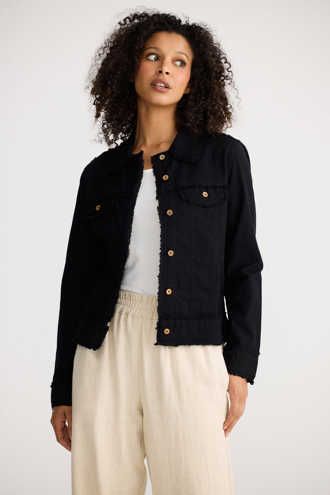 Woman wearing a black jacket with gold buttons on a white background