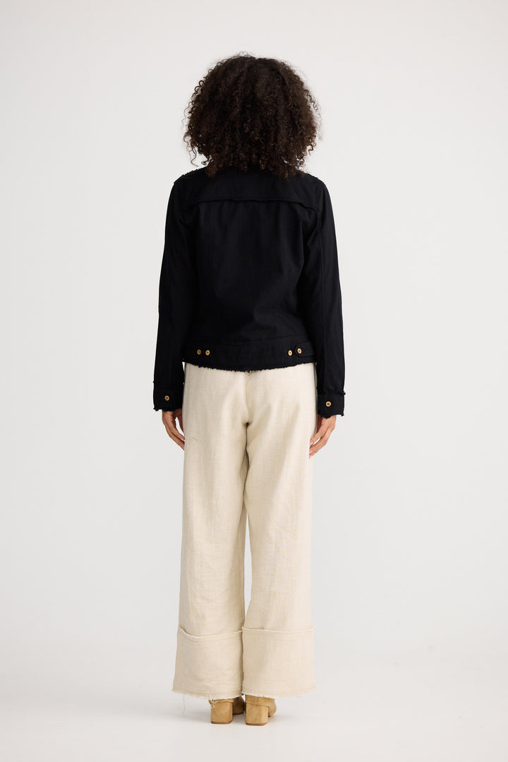Person wearing a black jacket and beige pants on a white background
