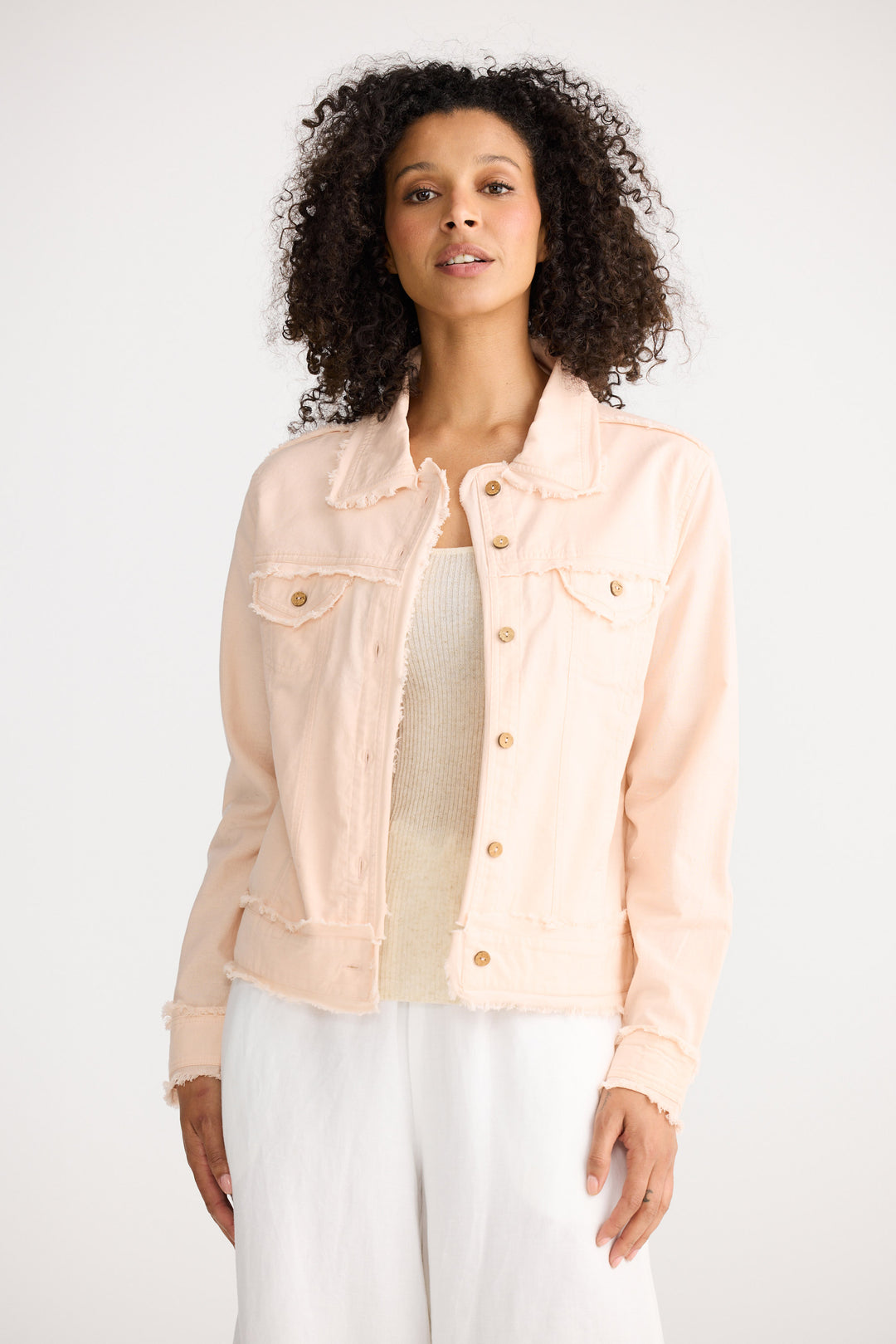 Woman wearing a light pink denim jacket on a white background