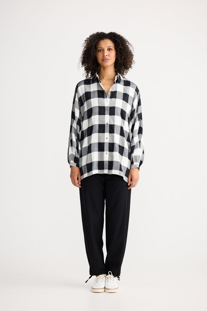 Woman wearing a black and white checkered shirt and black pants on a white background