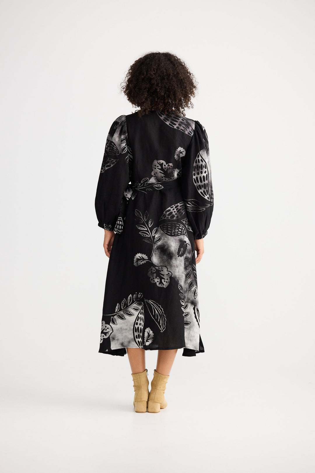 Person wearing a black dress with white abstract patterns on a white background