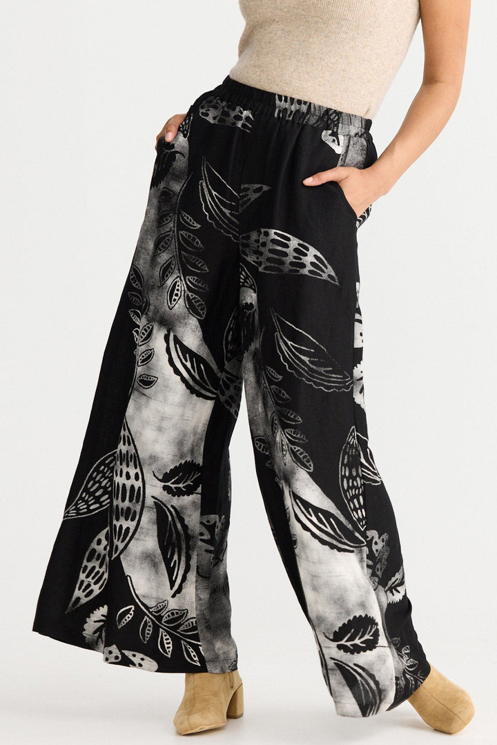 Woman wearing a sleeveless top and patterned pants on a white background