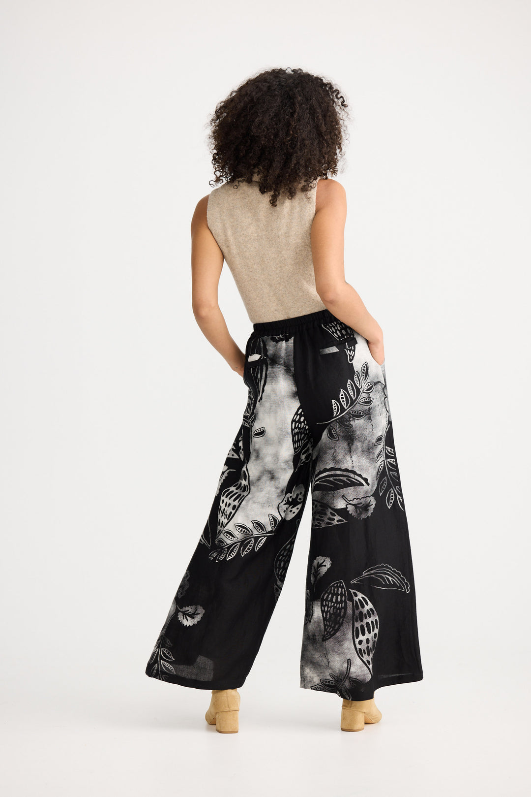 Woman wearing black wide-leg pants with white patterns on a white background