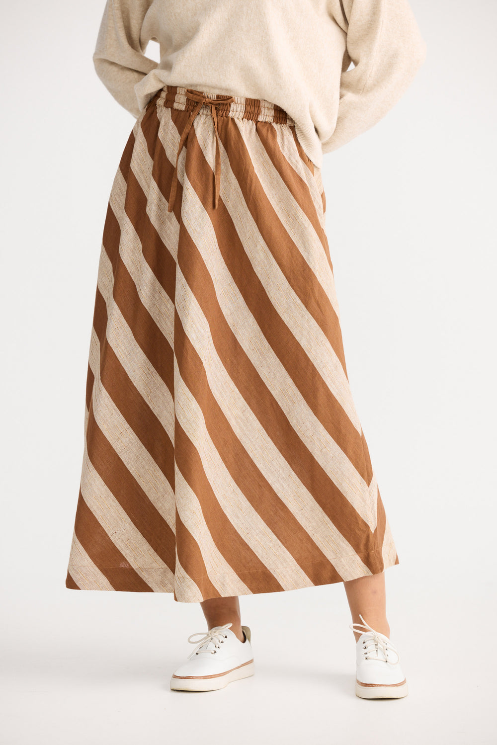 Person wearing a brown and beige striped skirt on a white background