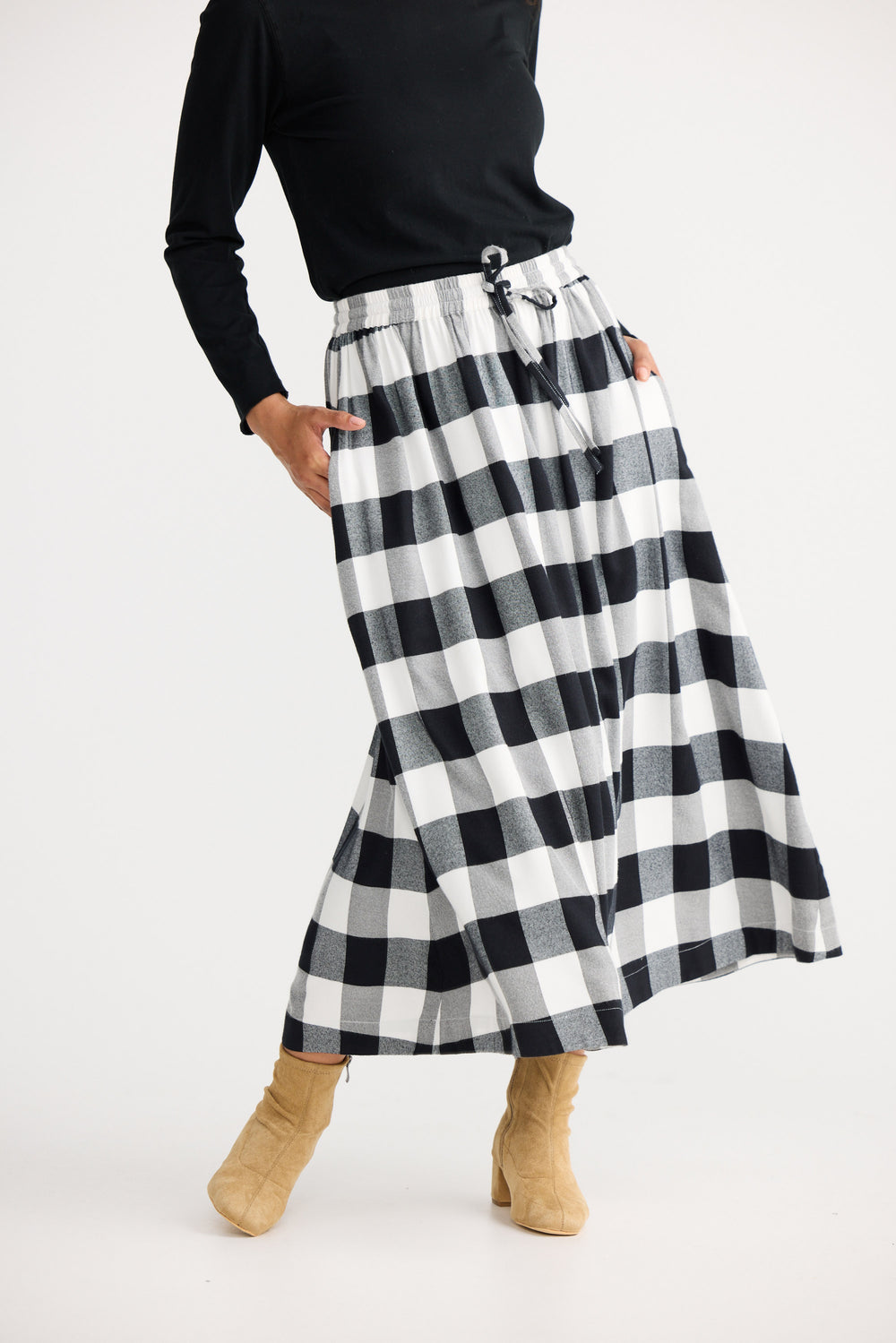 Person wearing a black and white checkered skirt on a white background