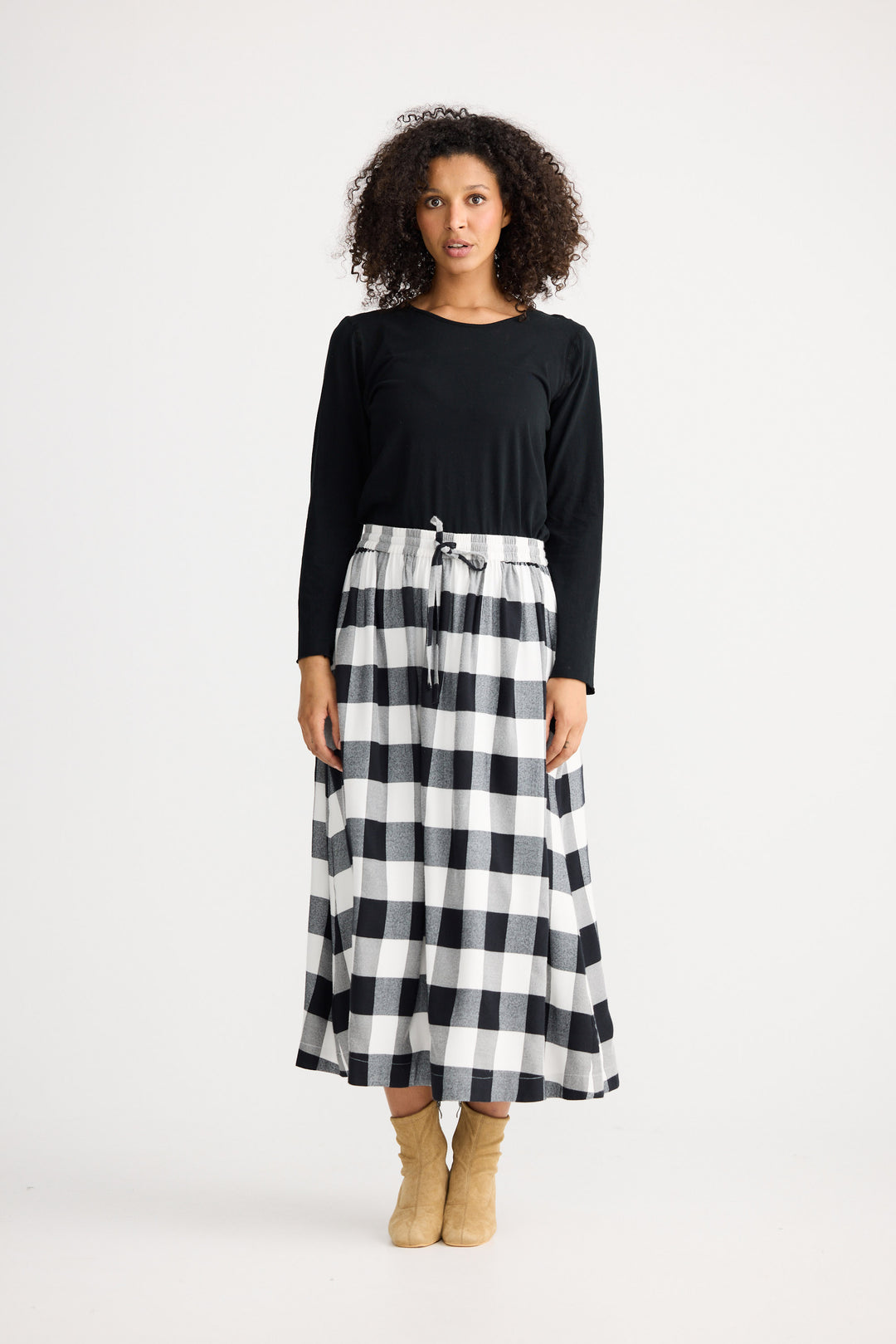 Woman wearing a black top and black and white checkered skirt on a white background