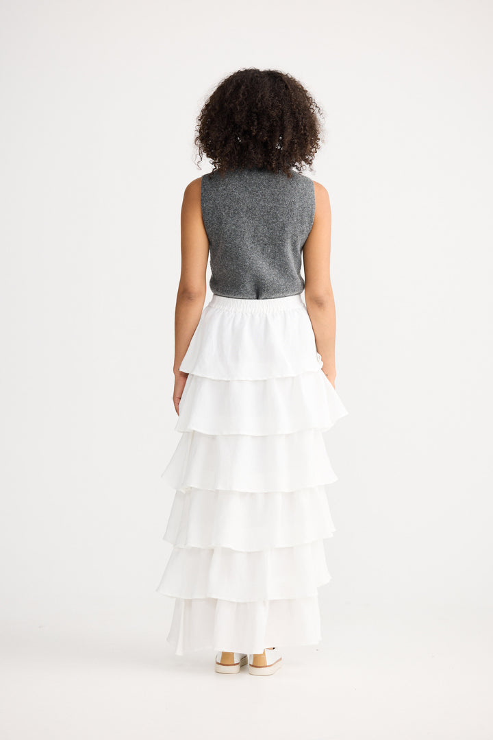 Woman wearing a gray sleeveless top and white tiered skirt on a white background