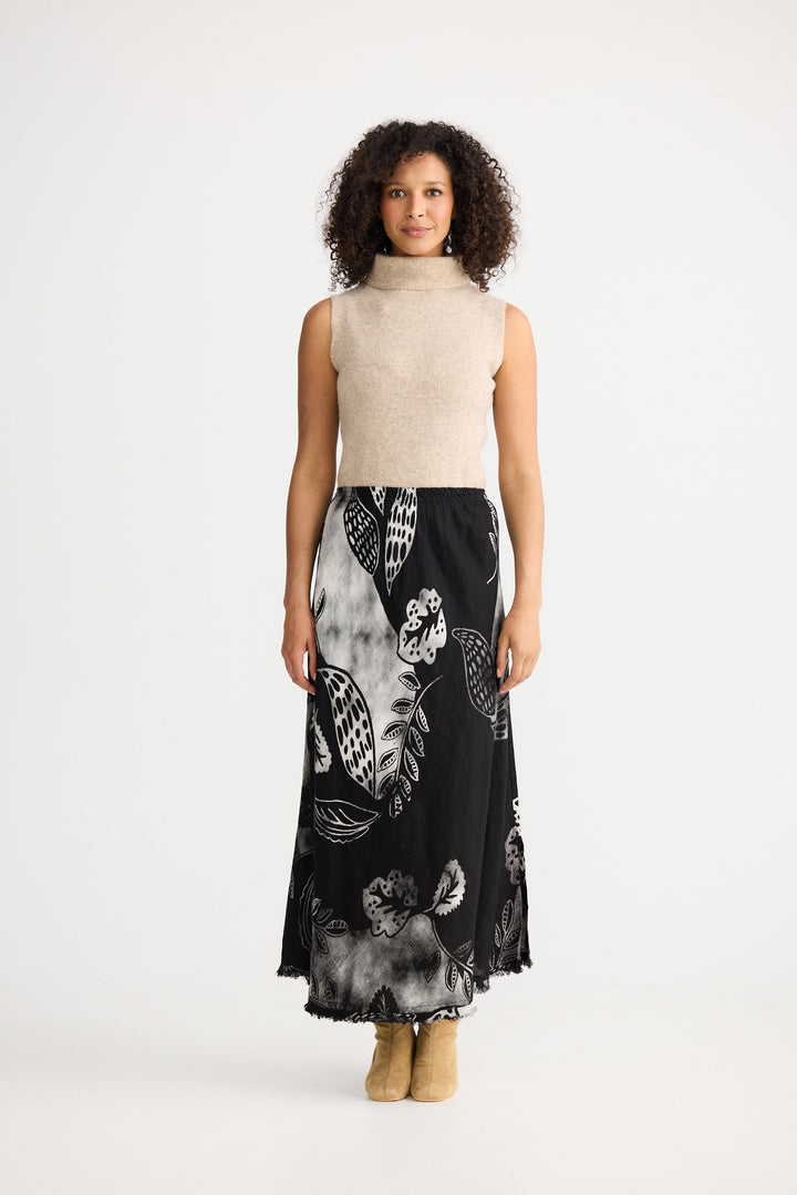 Woman wearing a black floral dress with a beige top on a white background