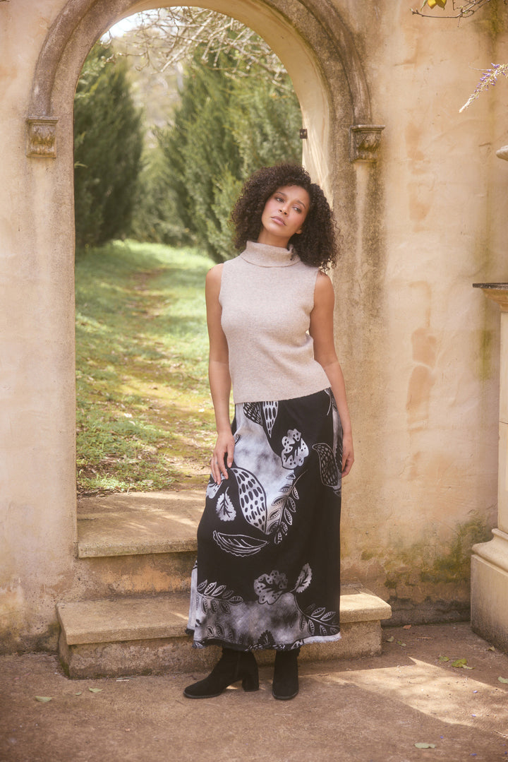 Woman standing under an archway in a garden