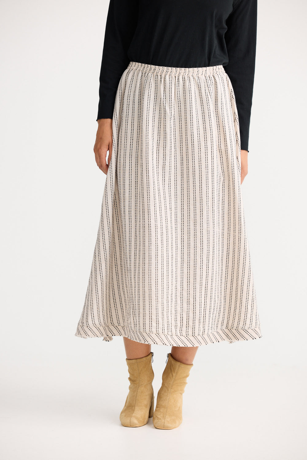 Person wearing a patterned skirt and black top on a white background