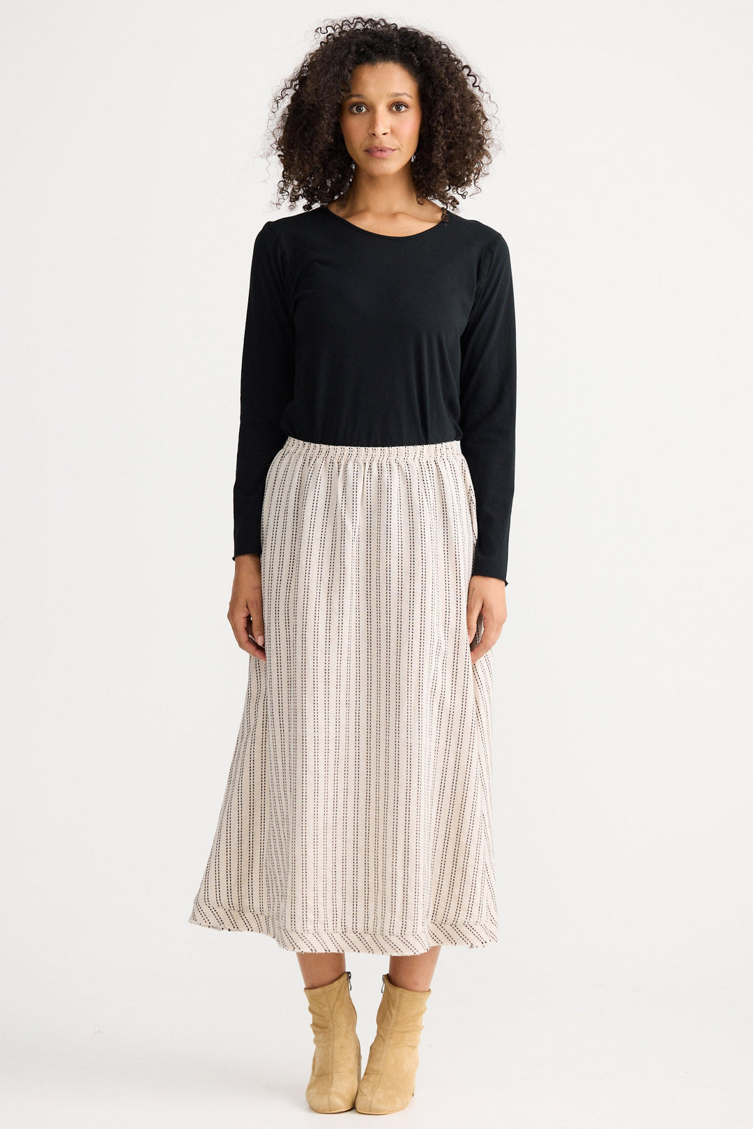 Woman wearing a black top and striped skirt on a white background