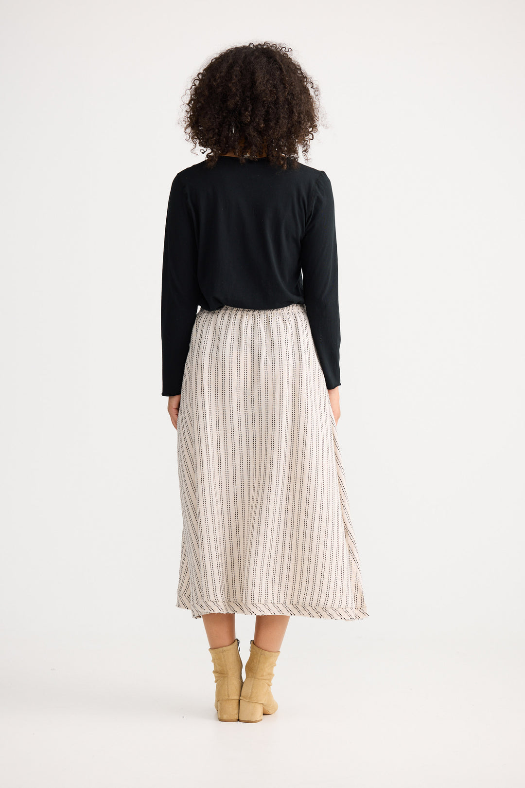 Person wearing a black top and white striped skirt on a white background