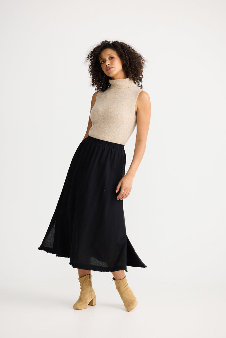 Woman wearing a beige sleeveless top and black skirt on a white background