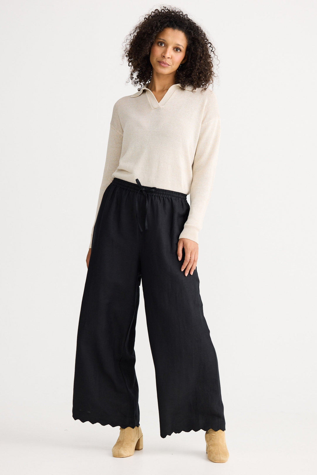 Woman wearing a white blouse and black wide-leg pants on a white background