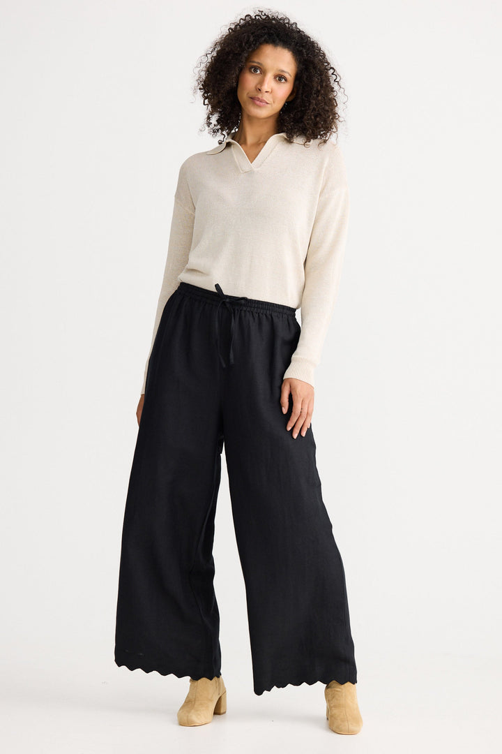 Woman wearing a white blouse and black wide-leg pants on a white background