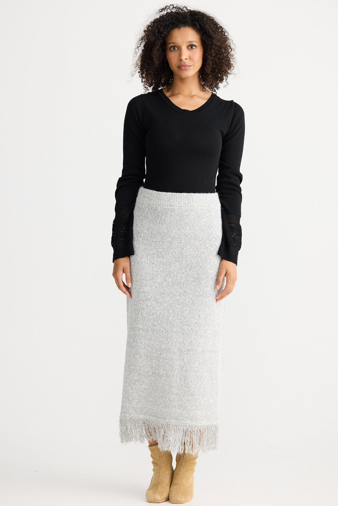 Woman wearing a black top and gray skirt on a white background