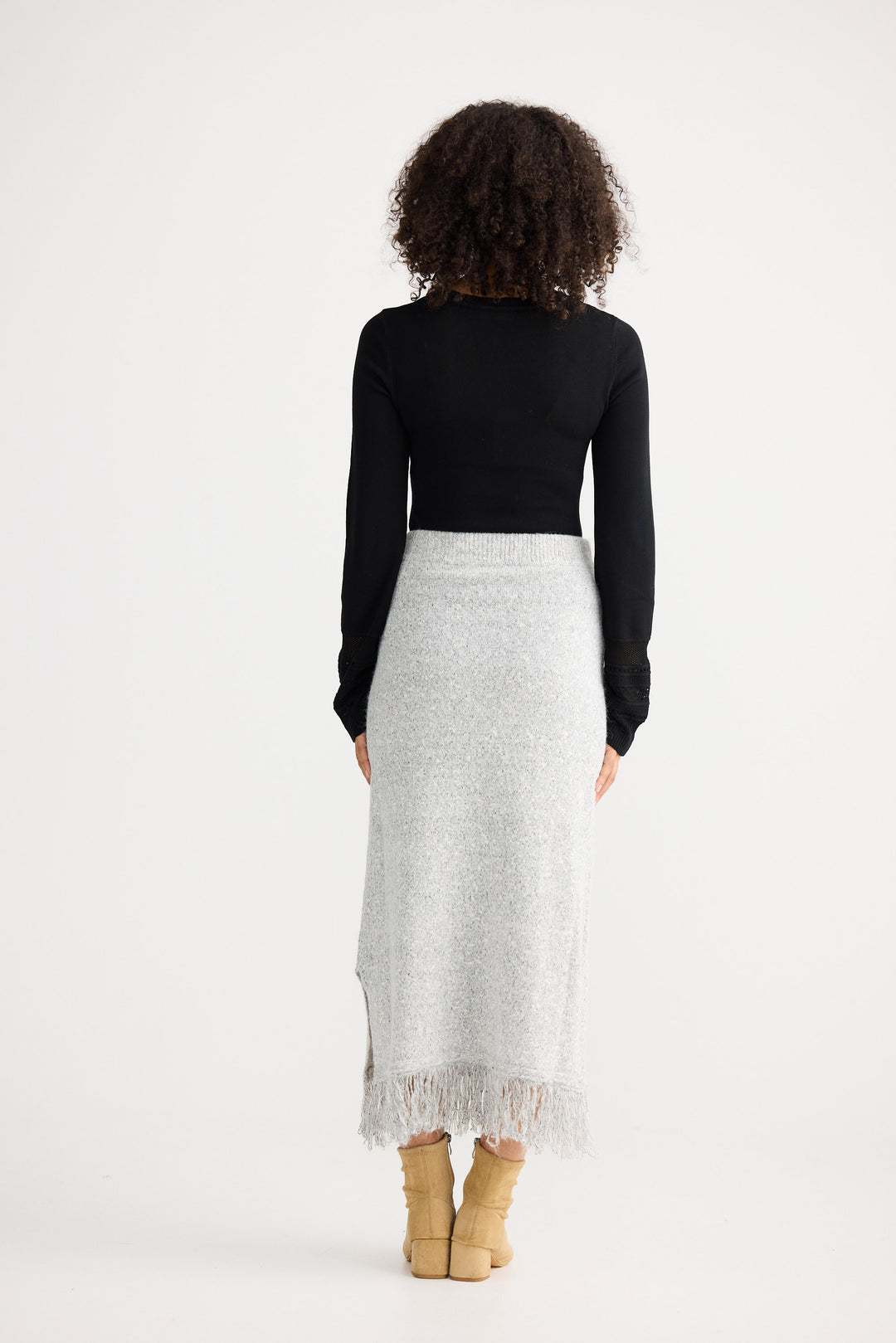 Woman wearing a black top and white skirt with lace hem on a white background
