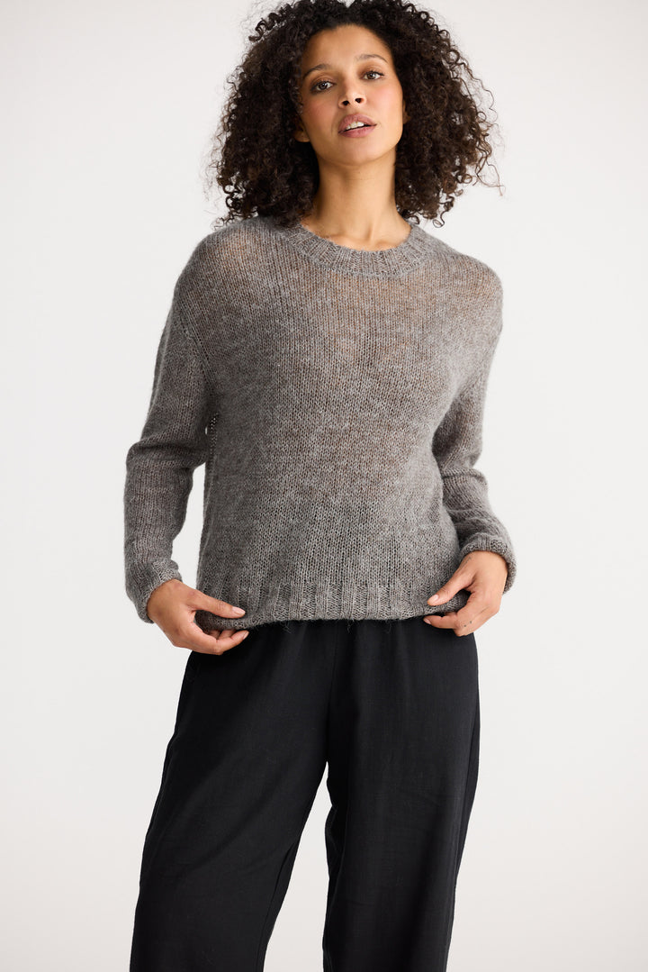 Model wearing charcoal Momento Knit, side view on white background