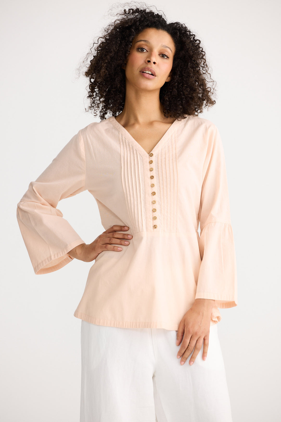 Woman wearing a light pink blouse with buttons on a white background