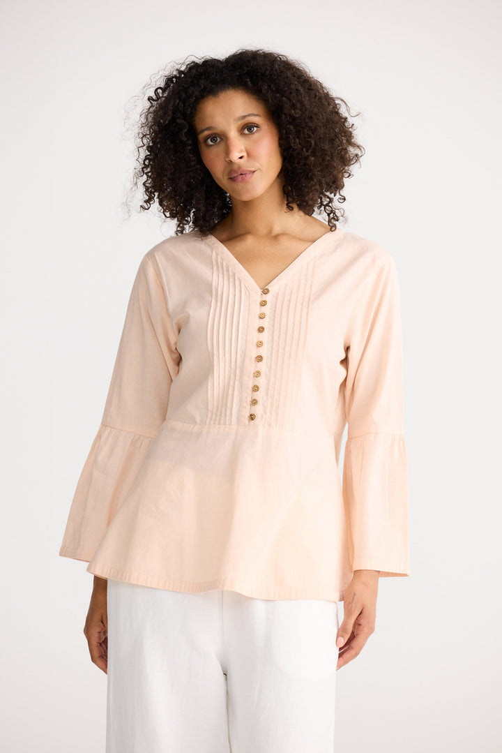 Woman wearing a light pink blouse with buttons on a white background