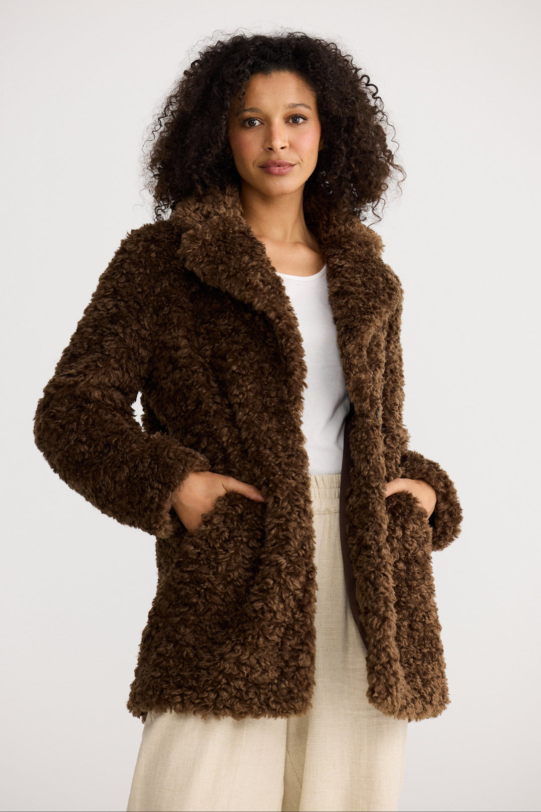 Woman wearing a brown fluffy coat against a white background