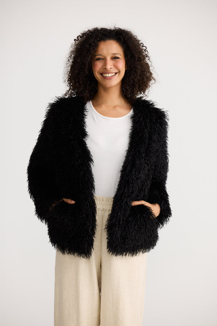 Woman wearing a black fluffy jacket on a white background