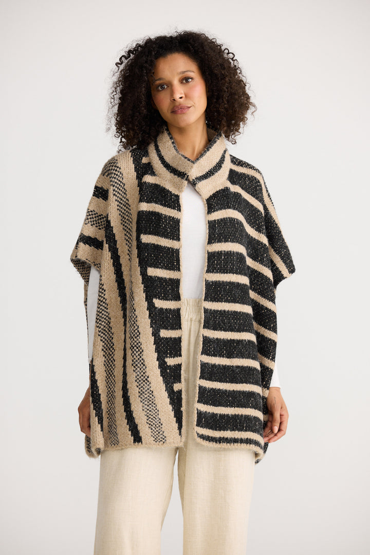 Woman wearing a striped poncho against a white background