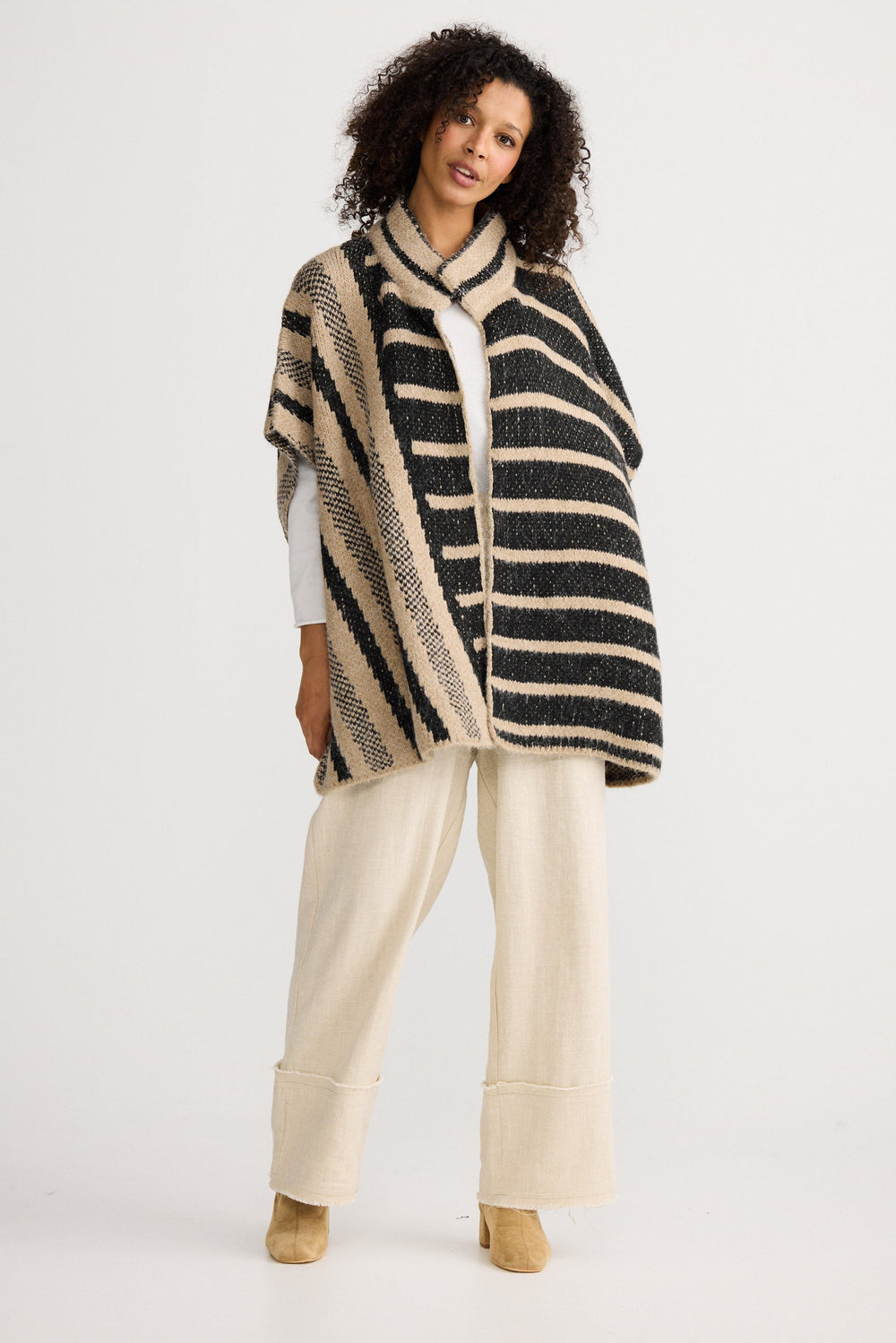 Woman wearing a striped poncho on a white background