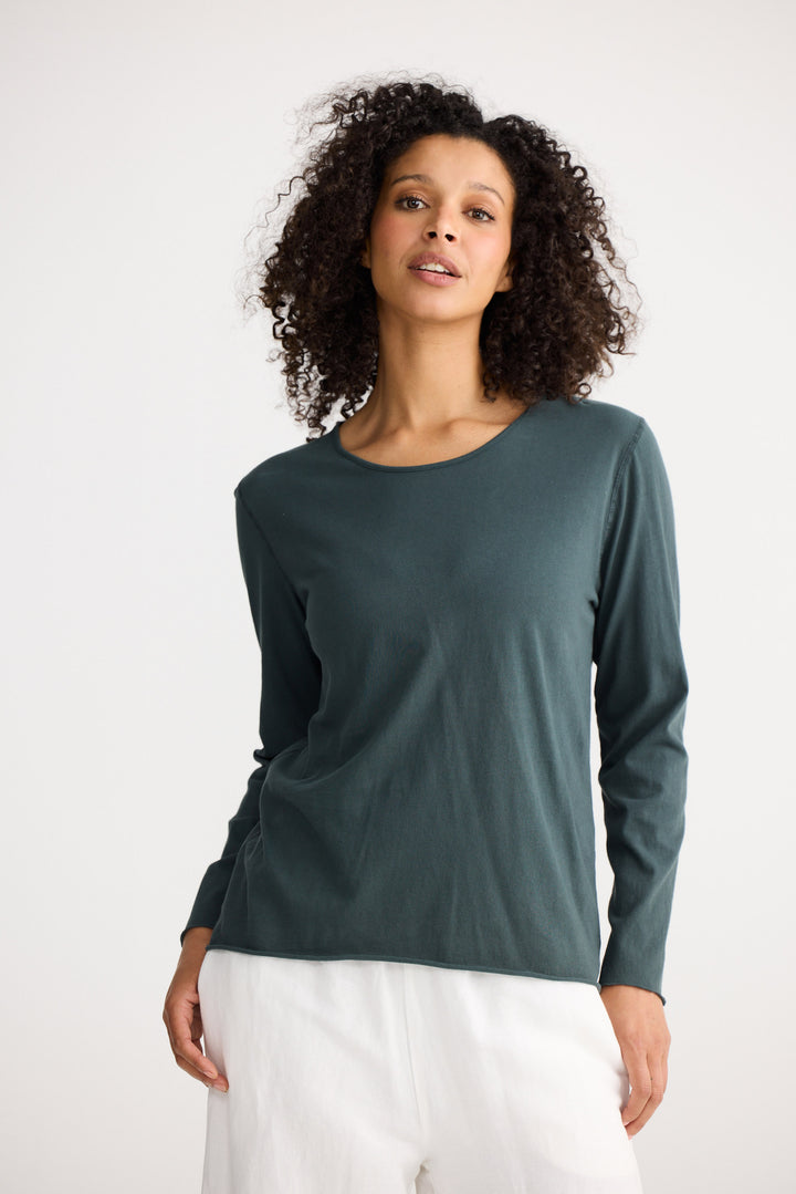 Model wearing slate Kasai Long Sleeve Top, angled front view on white background