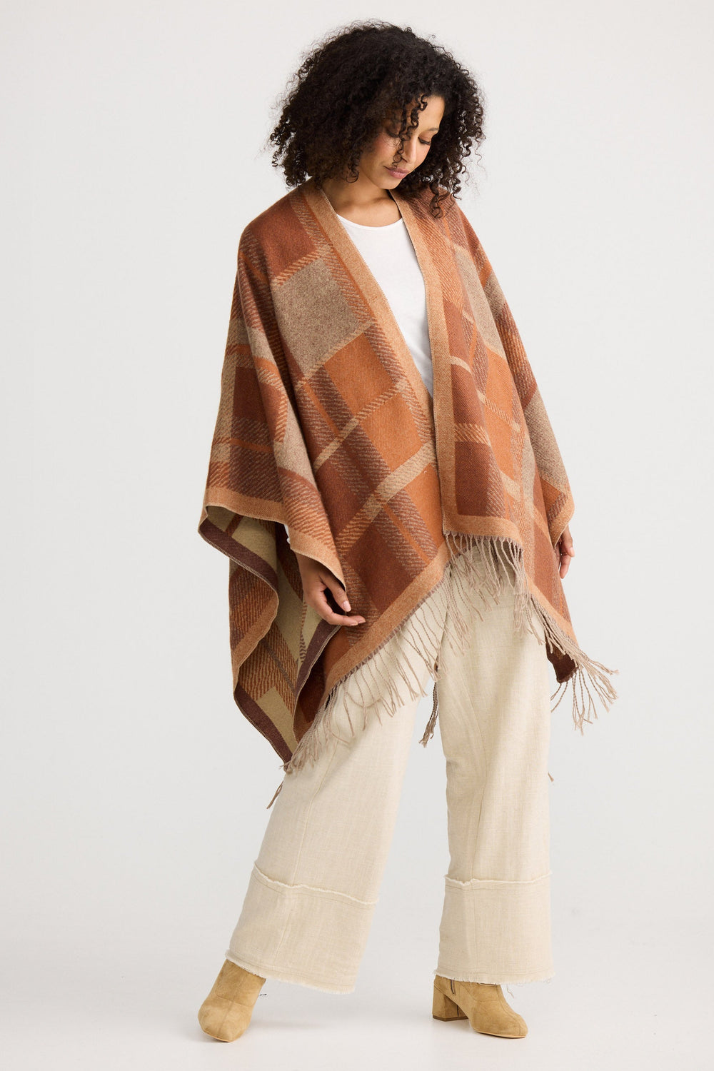 Woman wearing a brown plaid shawl over a white outfit on a white background