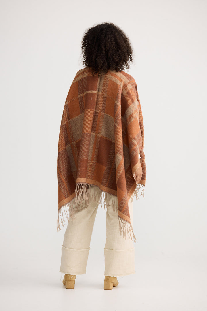 Person wearing a brown patterned poncho on a white background